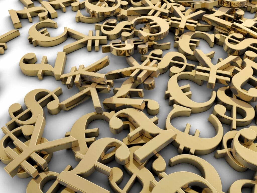 A pile of shiny gold currency symbols, including the dollar, euro, pound, and yen, scattered across a white surface.