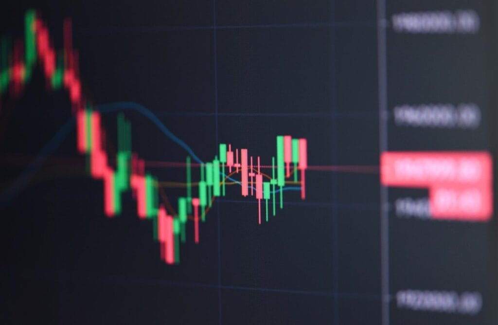 A close-up of a digital financial chart showing red and green candlesticks, indicating fluctuations in stock or cryptocurrency prices on a dark background.