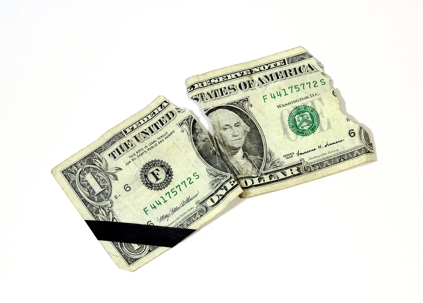 A torn one-dollar bill with a black diagonal stripe across the left piece, placed on a plain white background.